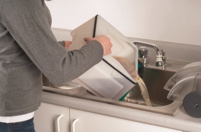 Woman dumping out dirty water tank into sink